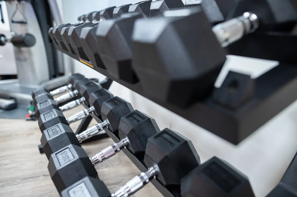 In the picture a detail of the hotel gym. There are some supports with dumbbells with black weights.